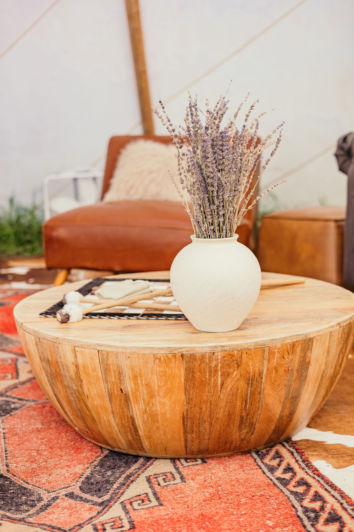 Wooden bowl centerpieces with dried lavender arrangements sit on an orange patterned rug.