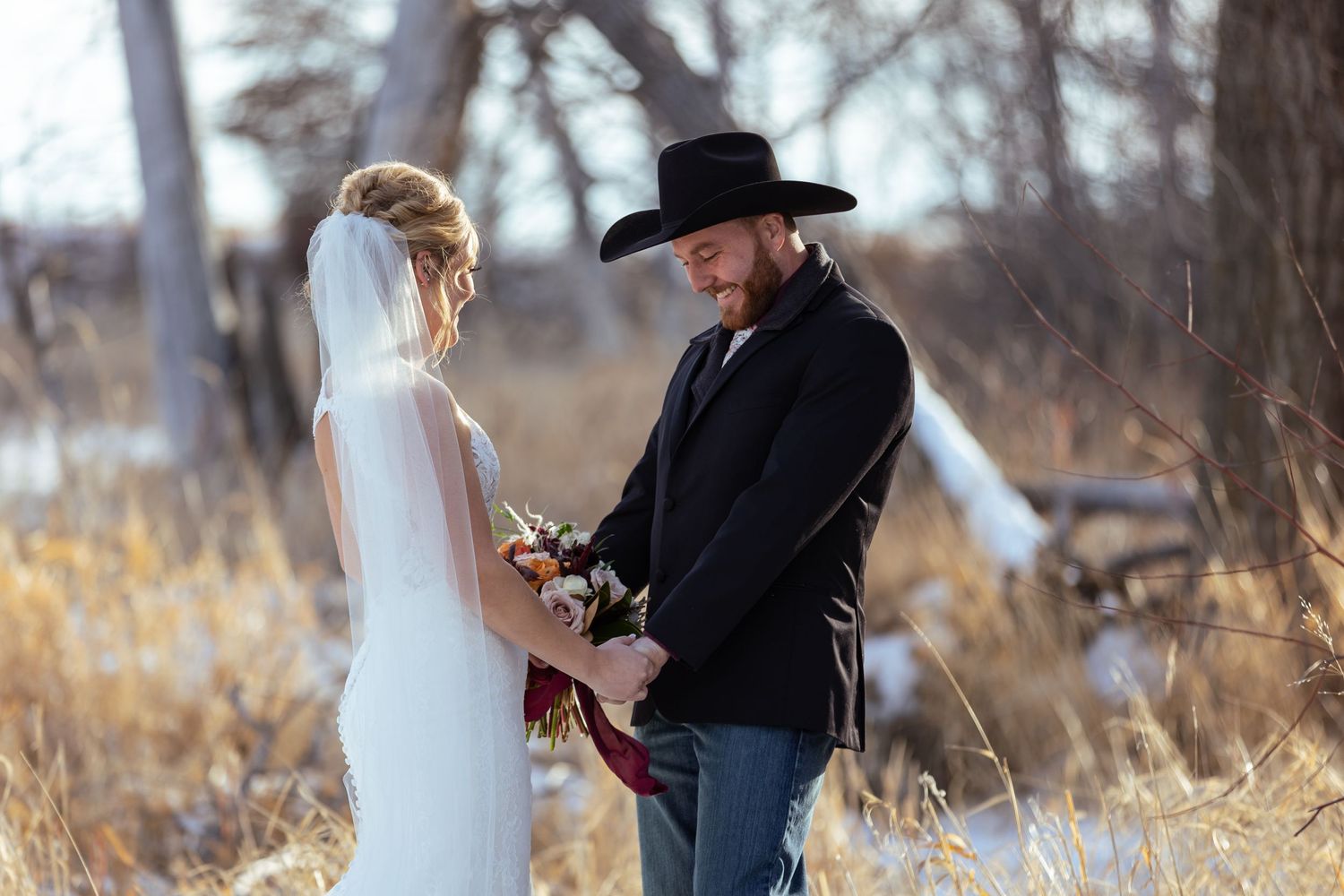 A western-themed wedding ceremony takes place outdoors against a backdrop of autumn foliage and bare trees.