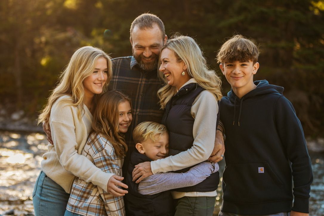 Family sharing warm embraces during golden hour in an outdoor setting.