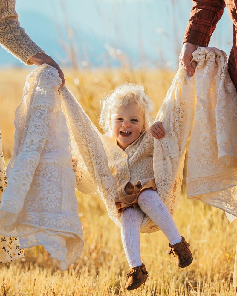 White lace dresses twirl in a golden field during sunset creating a dreamy atmosphere.