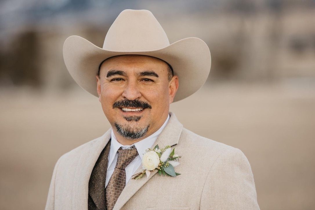 Western-style groom portraits in white cowboy hat and formal attire with boutonniere.
