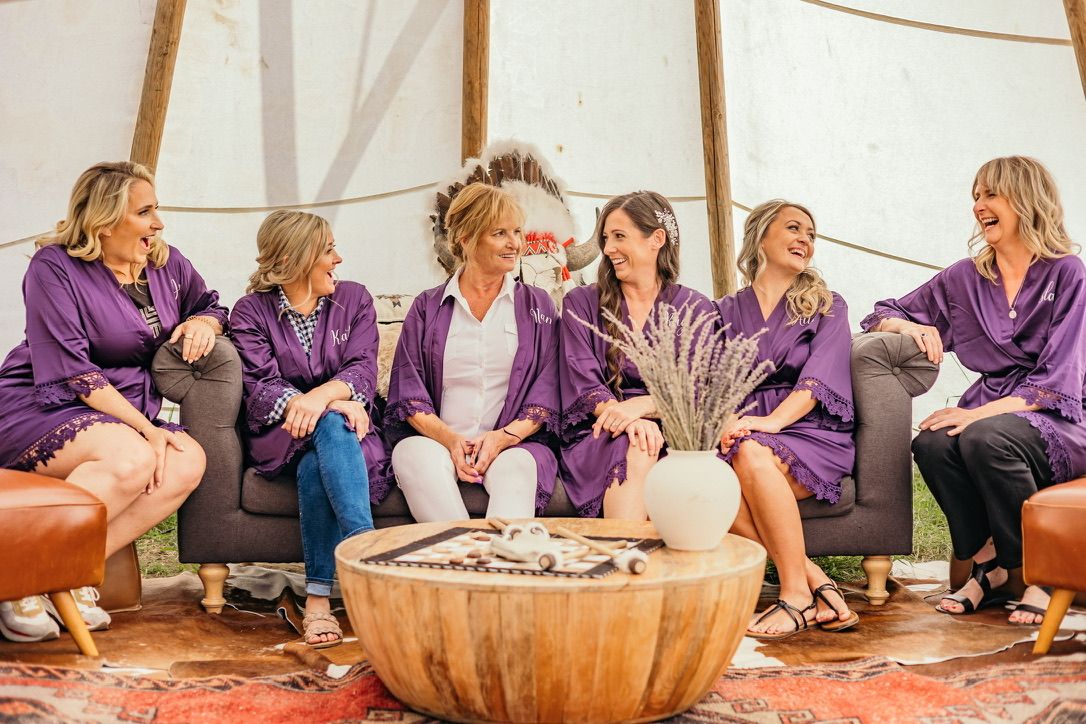 Wedding party relaxing in purple robes around outdoor fire pit.