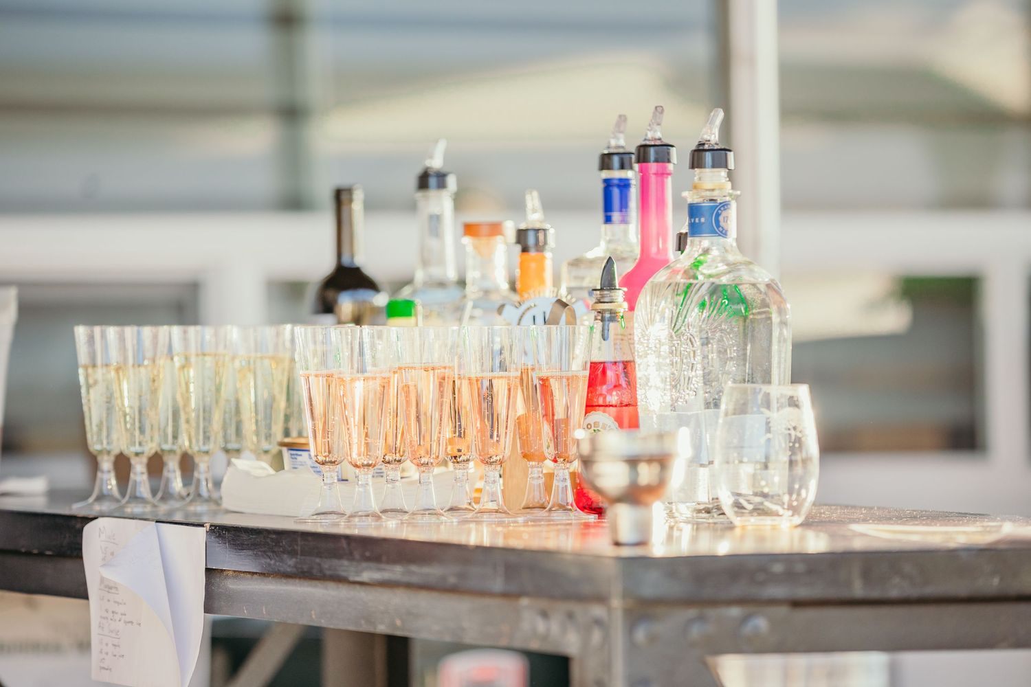 Row of empty champagne glasses and drink bottles set up for wedding reception.