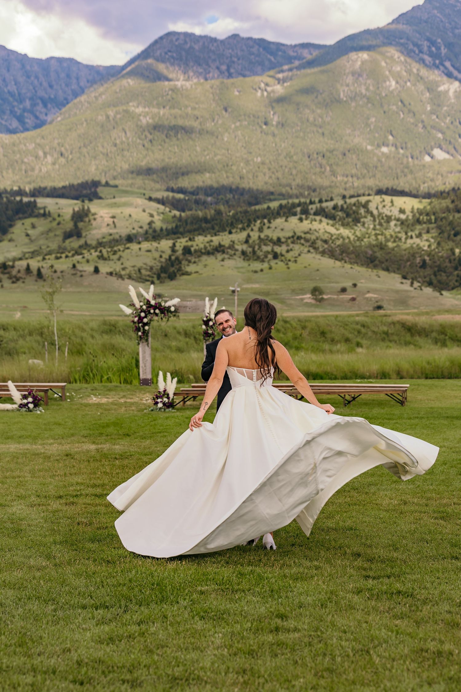 Wedding dress flowing in the wind against mountain landscape backdrop.
