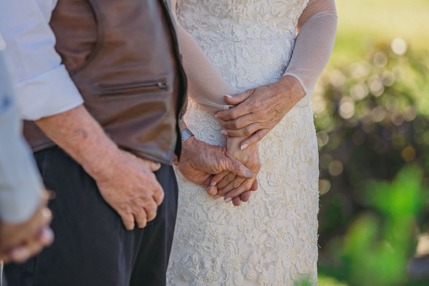 Close-up details of formal wedding attire in an outdoor setting.
