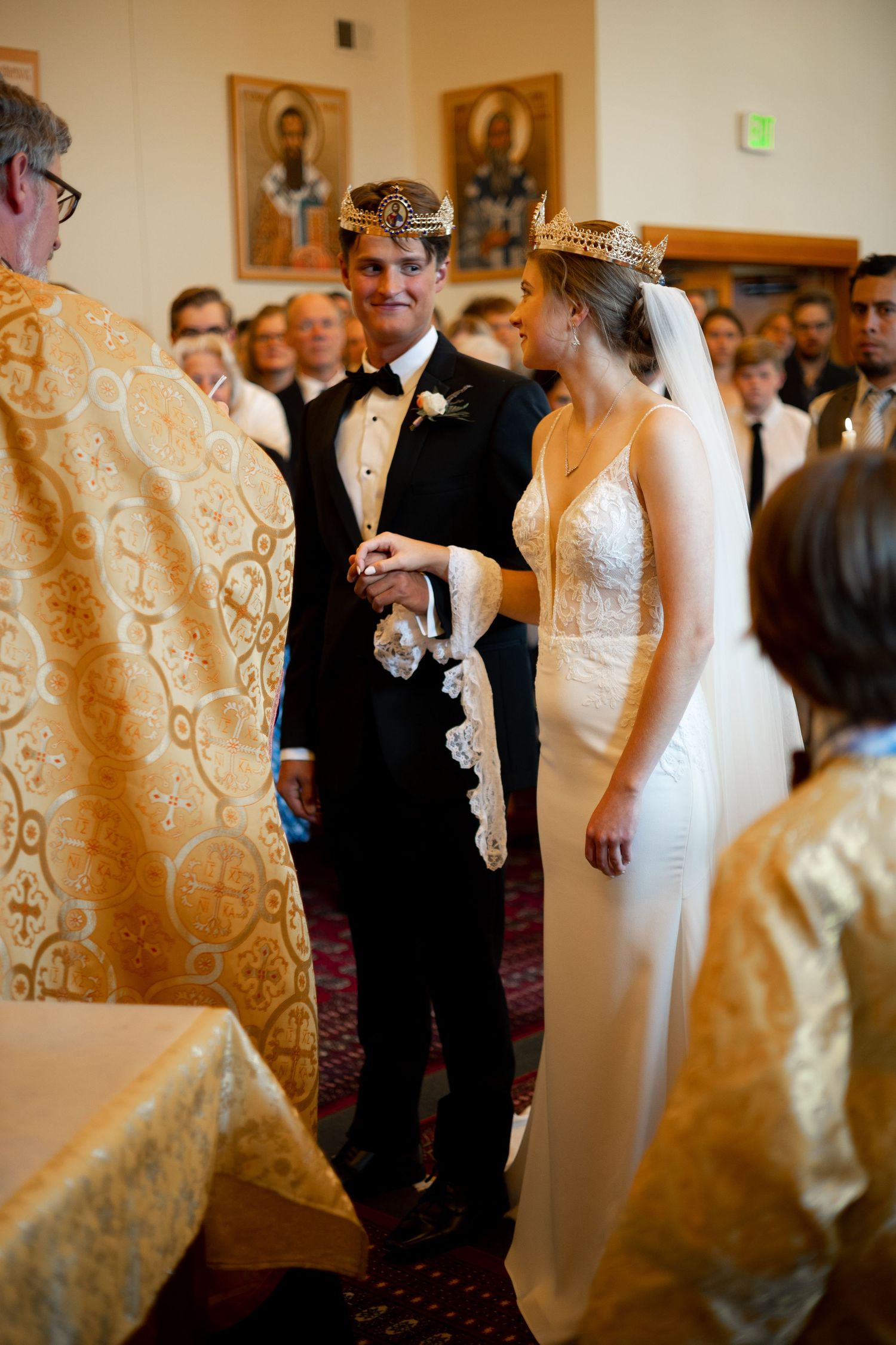 Wedding ceremony in an elegant venue with gold decor and formal attire.