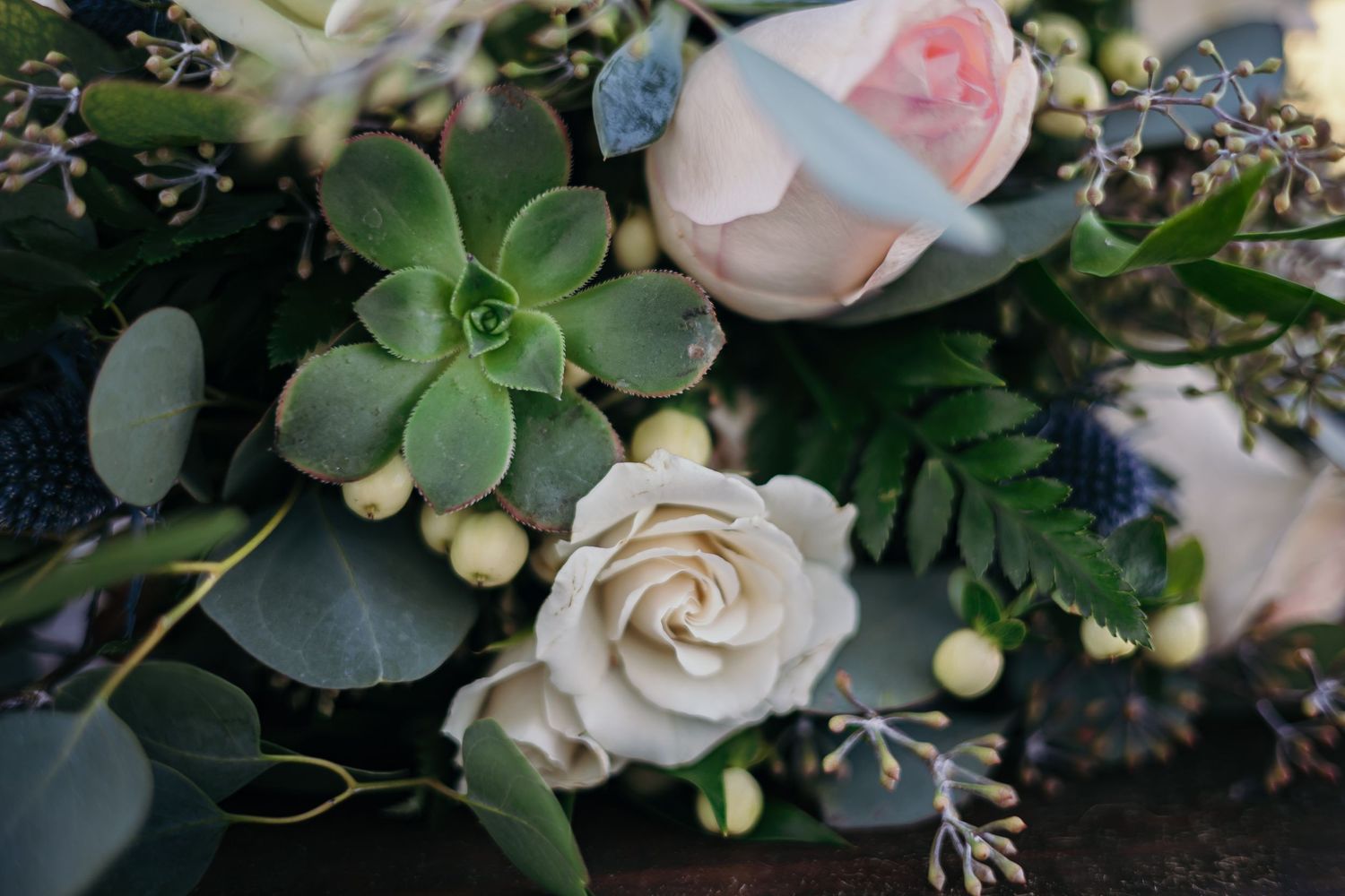 Close-up of romantic wedding flowers with blush roses, succulents, and eucalyptus leaves.