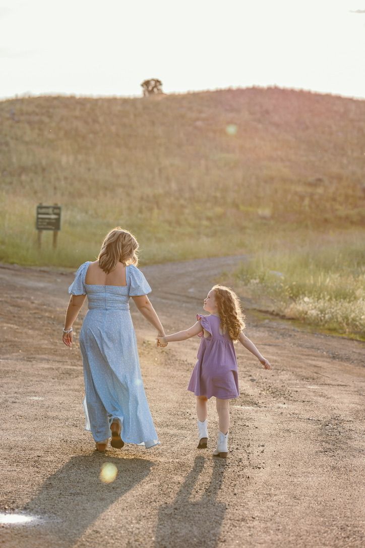 A tender moment between two figures walking on a dirt path at sunset in matching blue outfits.