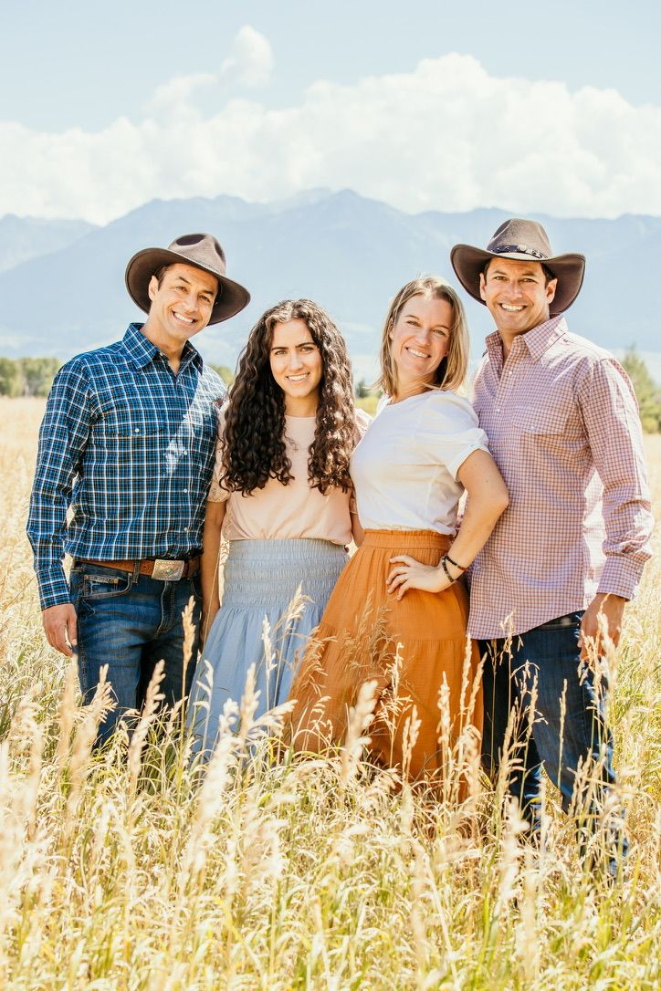 Family photo session in a golden wheat field with mountains in the background.