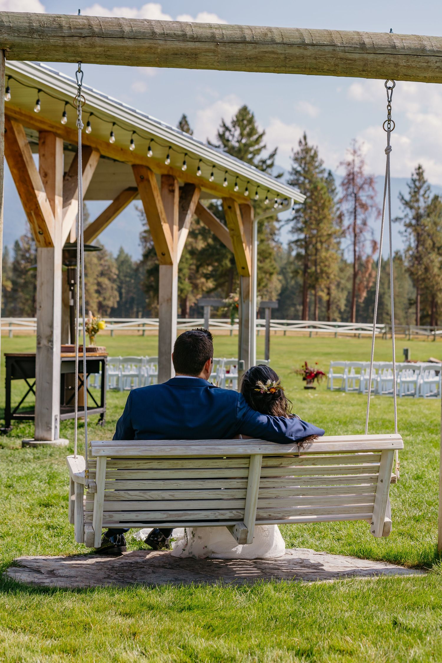 A playful wedding scene showing someone wearing a white strapless gown and blue sunglasses in a rustic venue with stone walls.