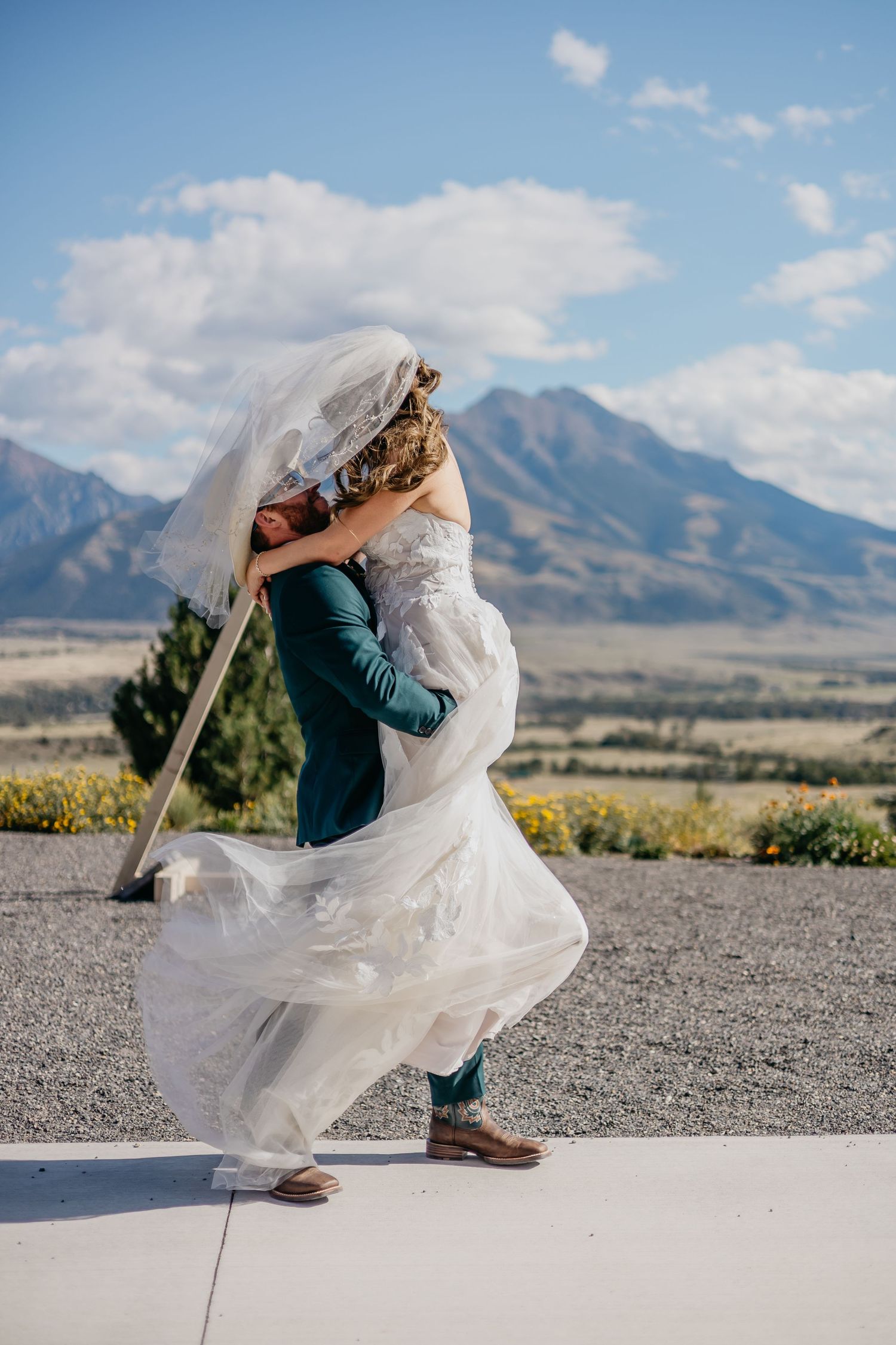 Wedding couple embraces with flowing dress against mountain backdrop.