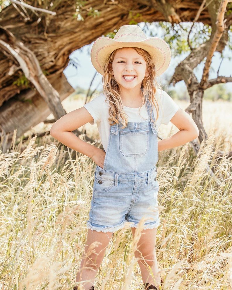 Summer portraits in a field with straw hat and denim overalls.