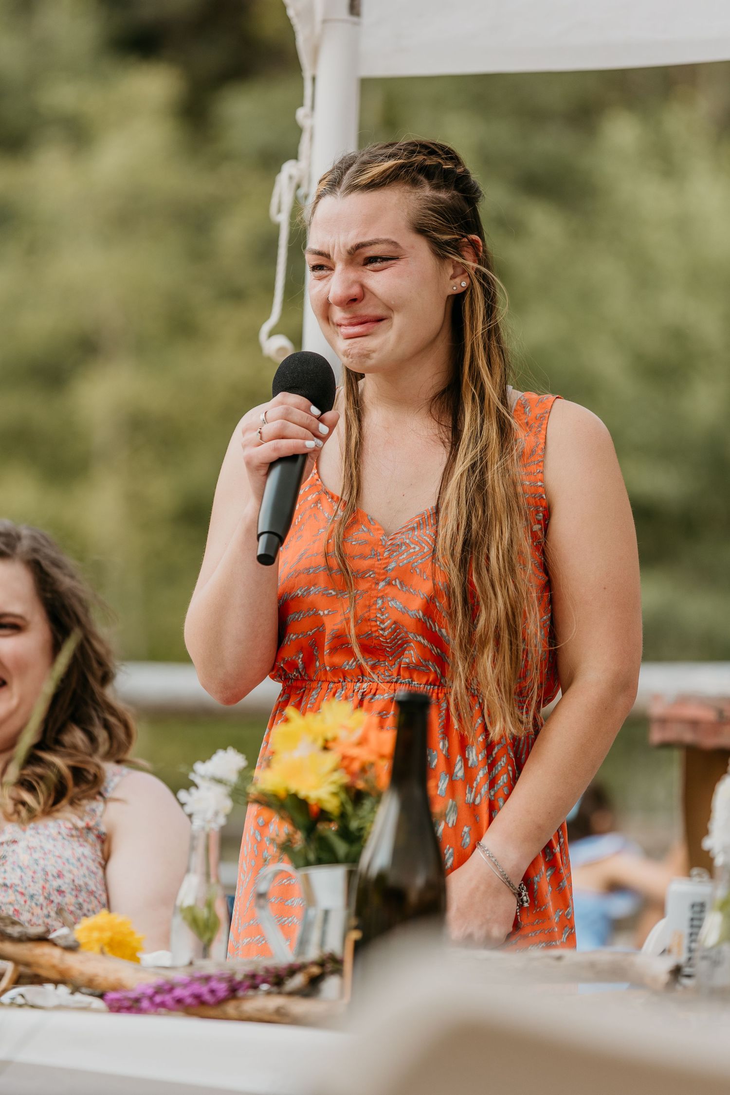 Guest in coral dress laughing during outdoor wedding reception.
