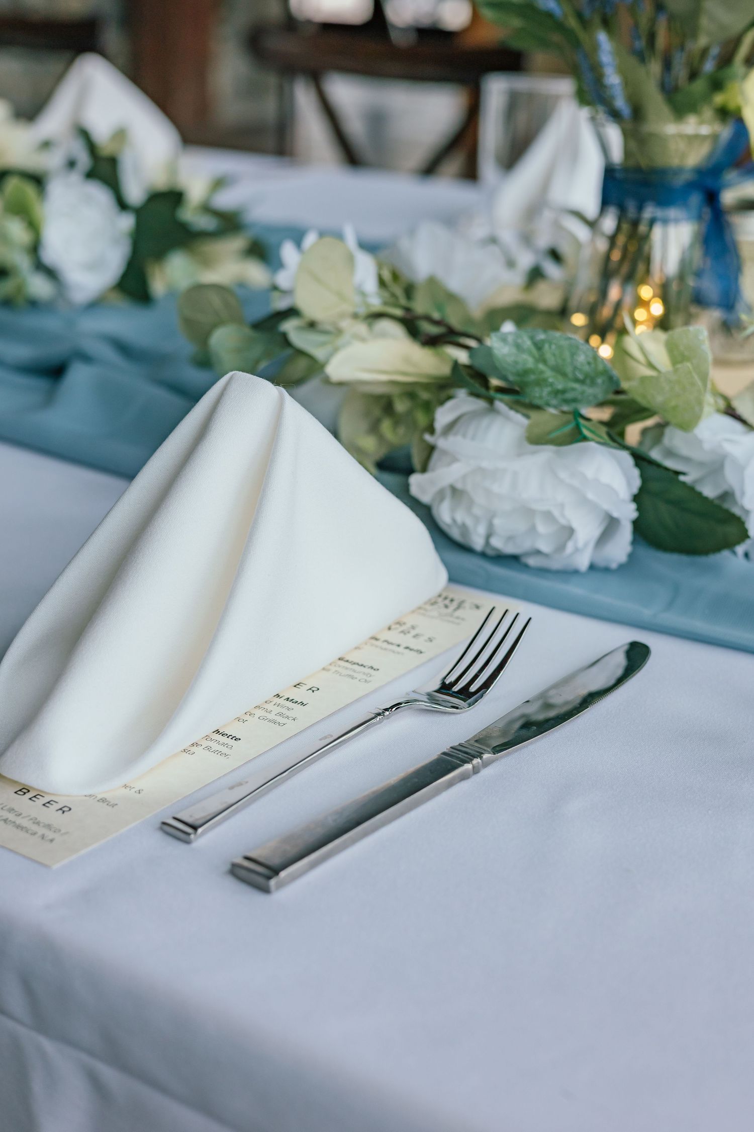 Elegant place setting with white napkin, silverware and floral decorations.