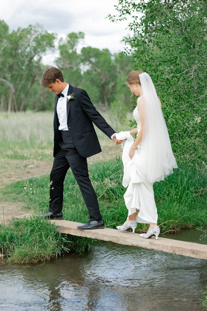 A sequence showing a couple in wedding attire crossing a wooden plank over water.