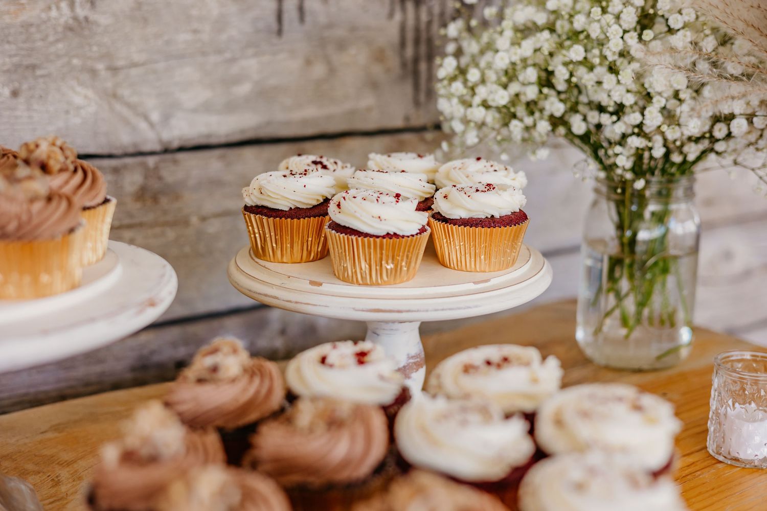 Elegant dessert display featuring various decorated cupcakes and baby's breath flowers.