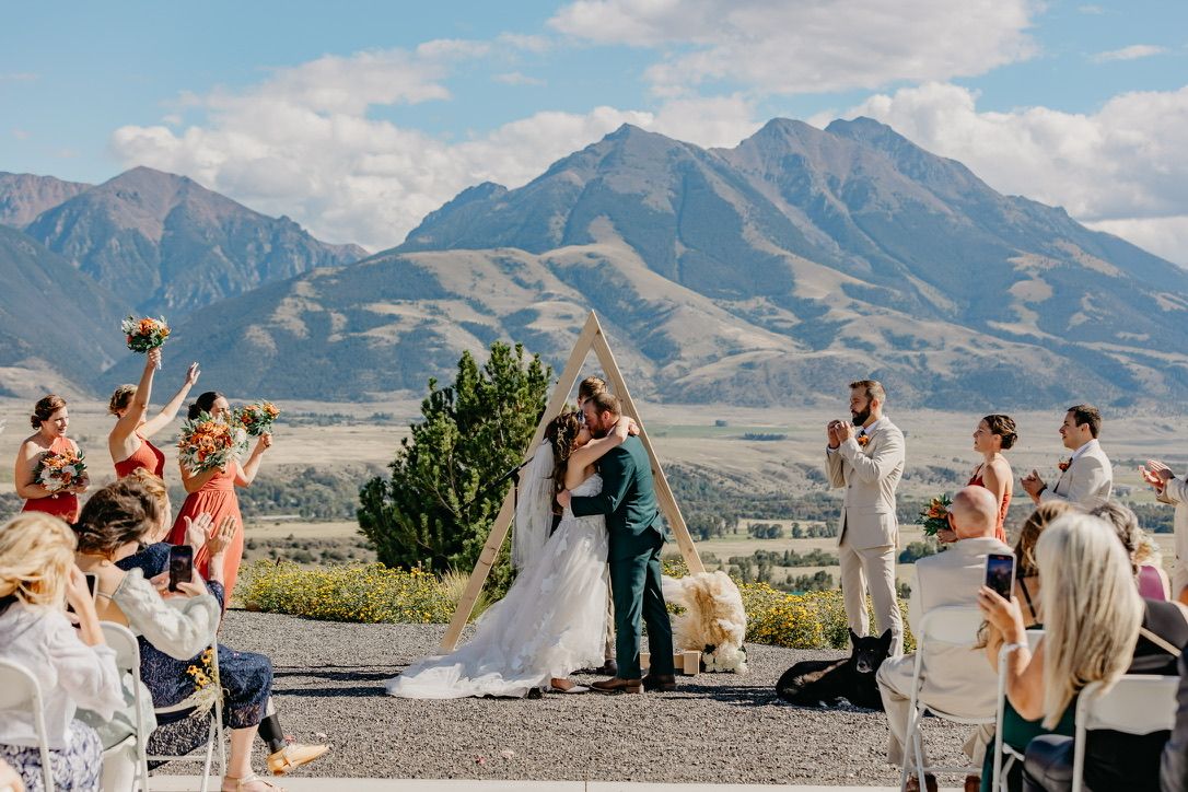 Mountain wedding ceremony with guests celebrating against dramatic peaks in background.