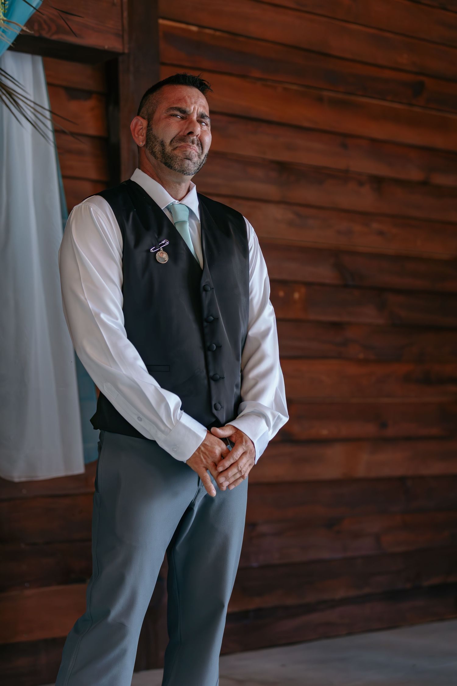Person in formal attire standing against rustic wooden wall background.