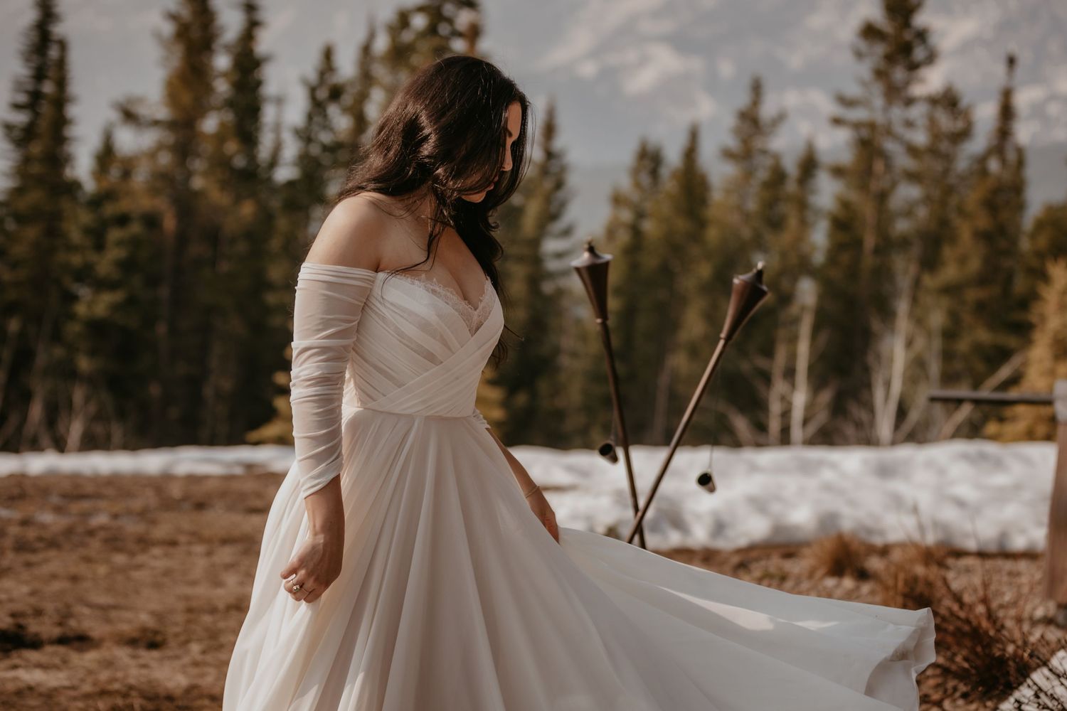 Snowy mountain wedding scene with evergreen trees in background.