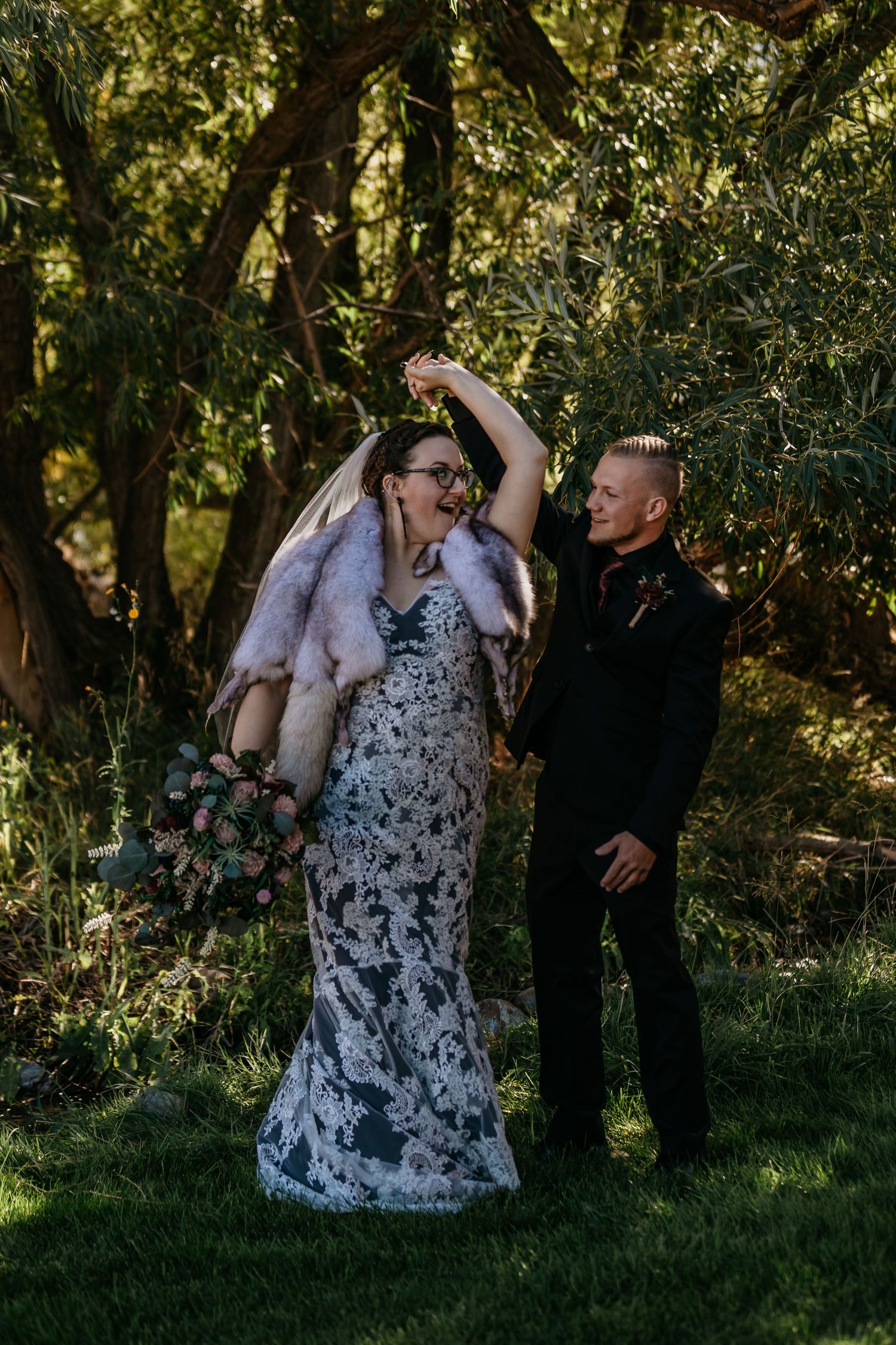 Wedding couple dancing and laughing together in a green garden setting.