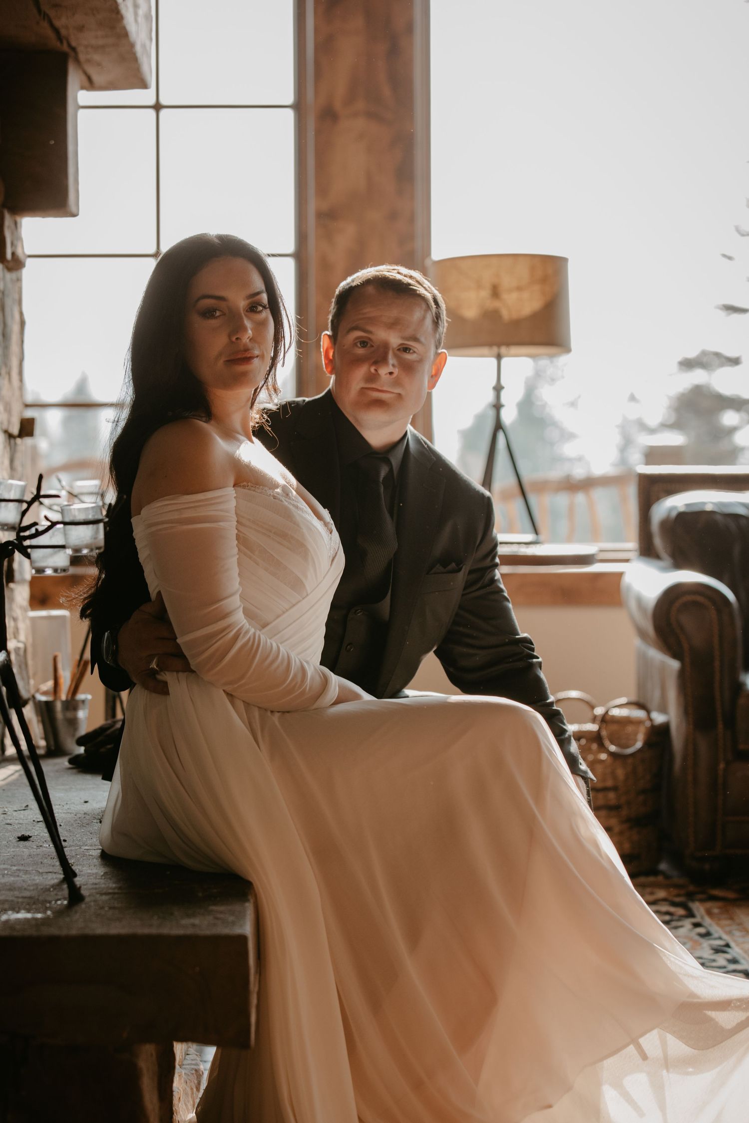 Couple shares intimate moment in rustic venue with wooden beams and natural lighting.