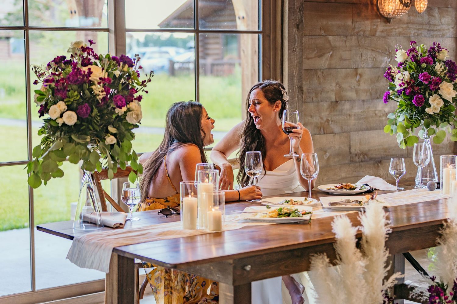 Wedding reception table setting with two people dining and floral arrangements.