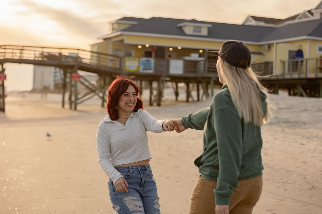 Couple dancing together on sandy beach during sunset.
