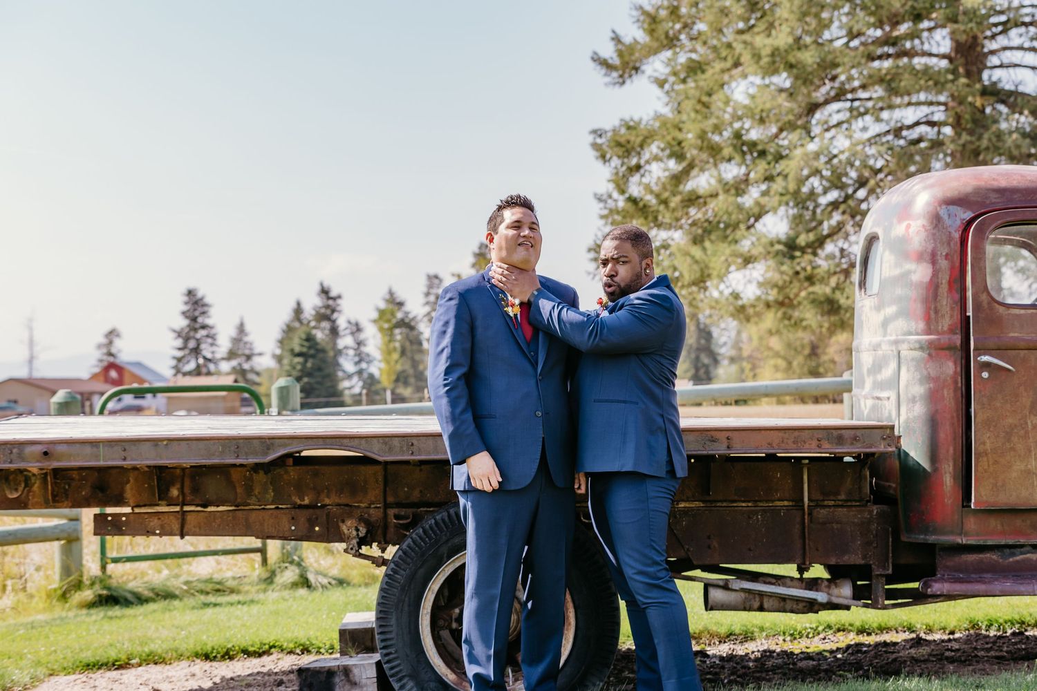 Couple embracing near vintage trucks during outdoor photo session.