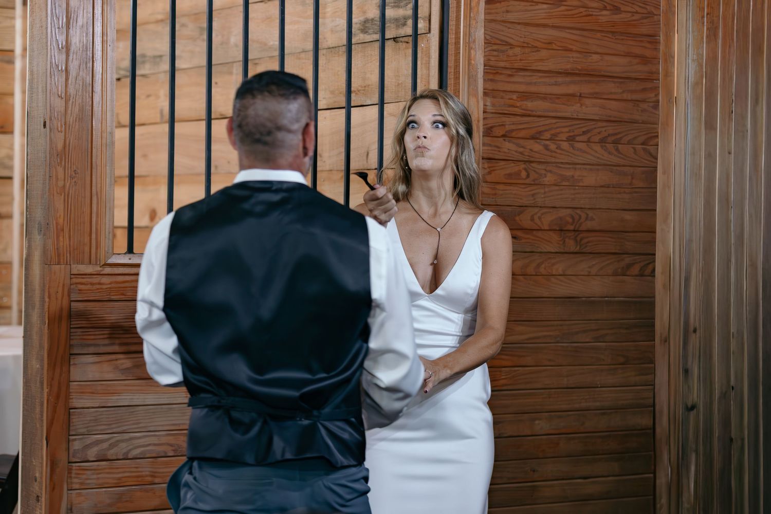 Intimate moment captured during wedding ceremony against wooden wall backdrop.