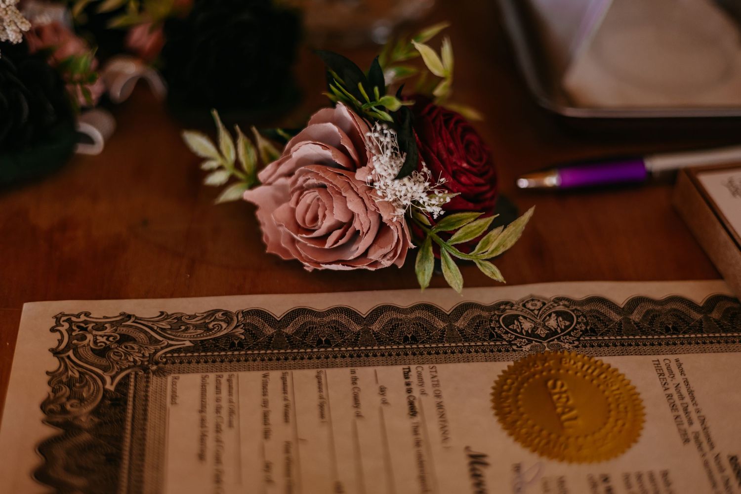 Wedding ceremony details with decorative marriage certificate and pink floral accents.