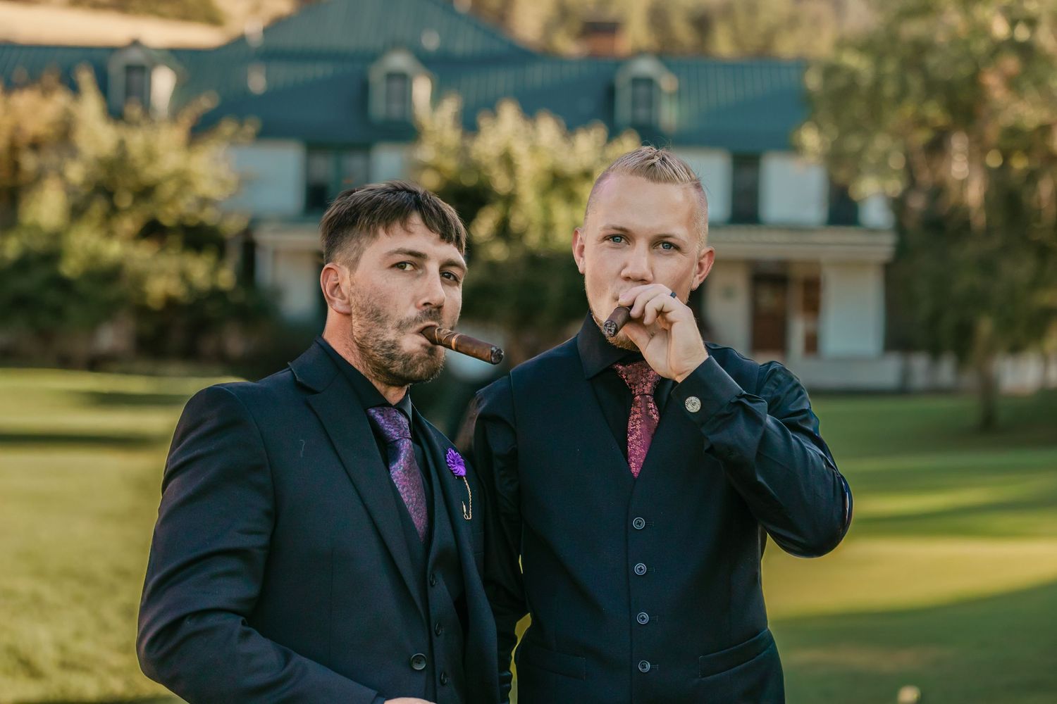 Groomsmen share laughs and conversation on a sunny day outdoors.