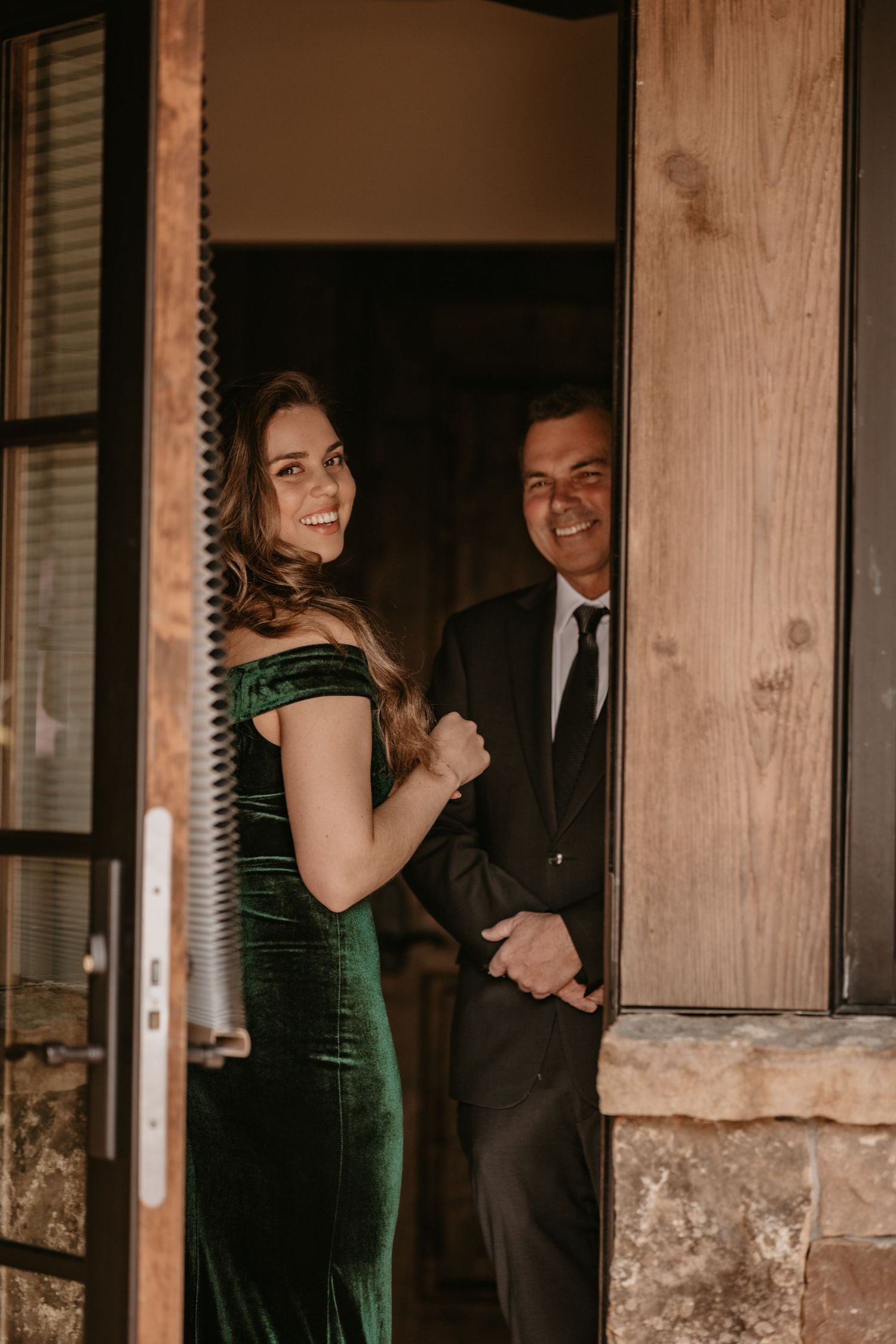 Romantic moment captured through wooden doorframe in warm lighting.