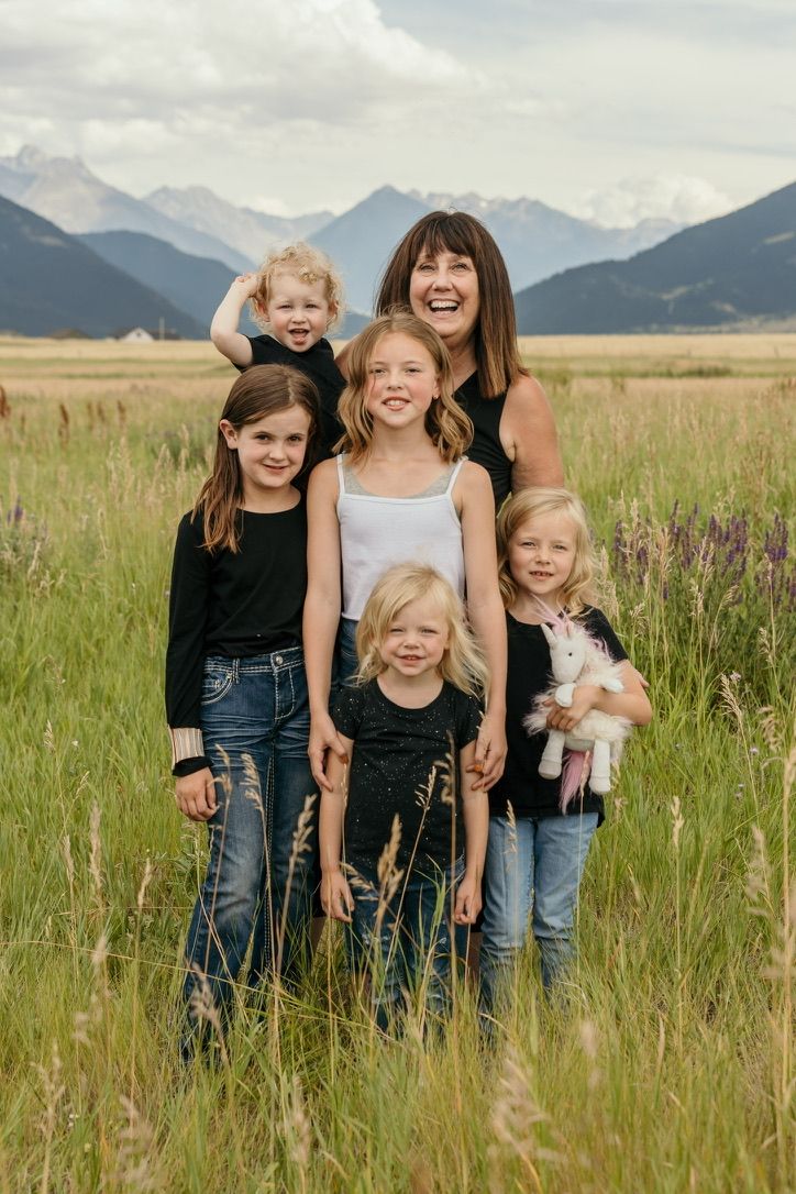 Group portrait in mountain meadow with wildflowers and scenic backdrop.
