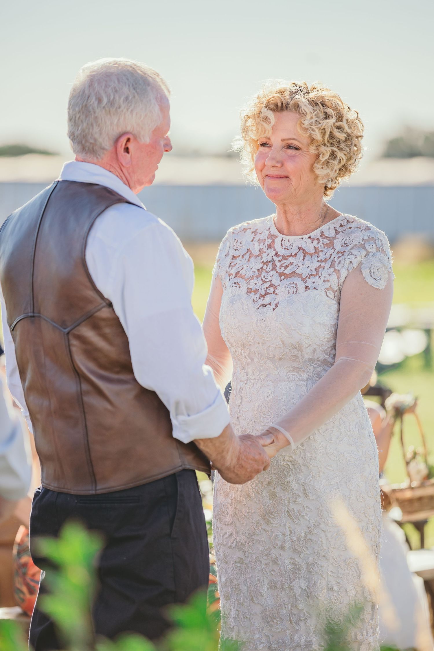 Couple in formal attire standing together during outdoor wedding celebration.