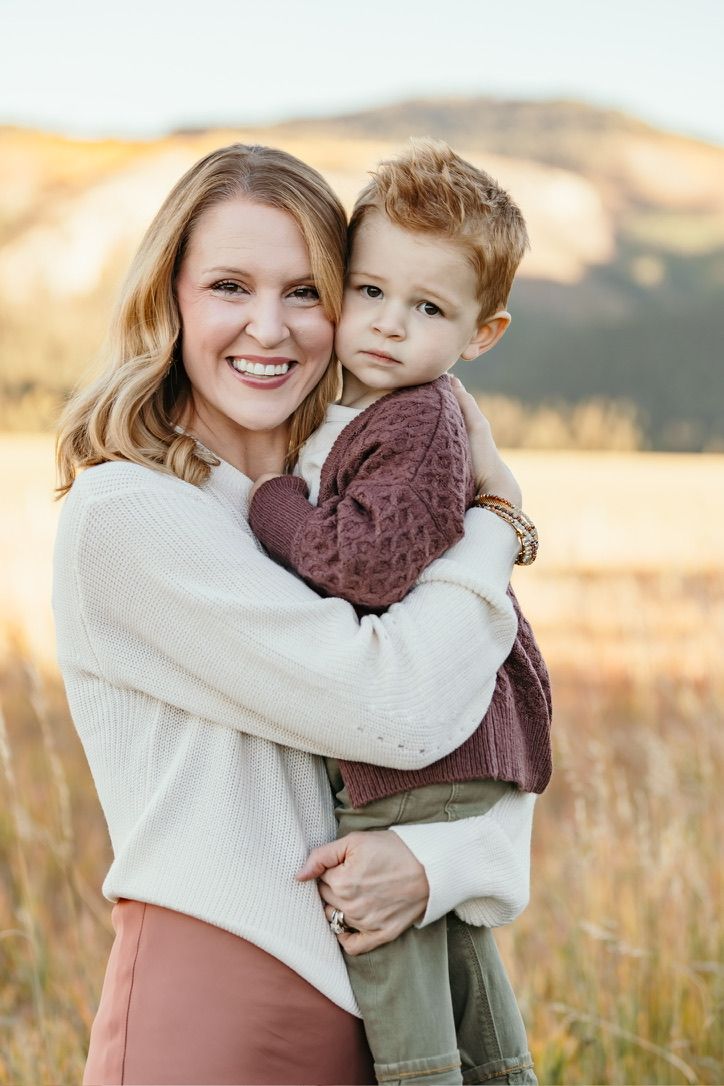 Outdoor portrait session in field with warm autumn lighting and mountain backdrop.