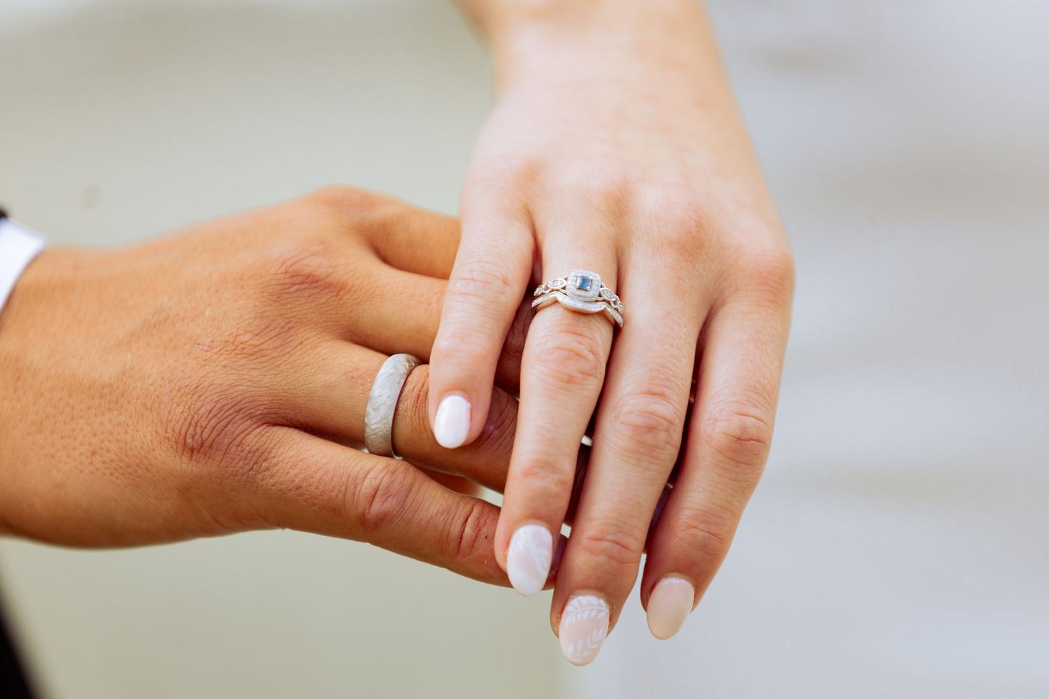 Close-up of wedding rings and manicured hands showing engagement ring.