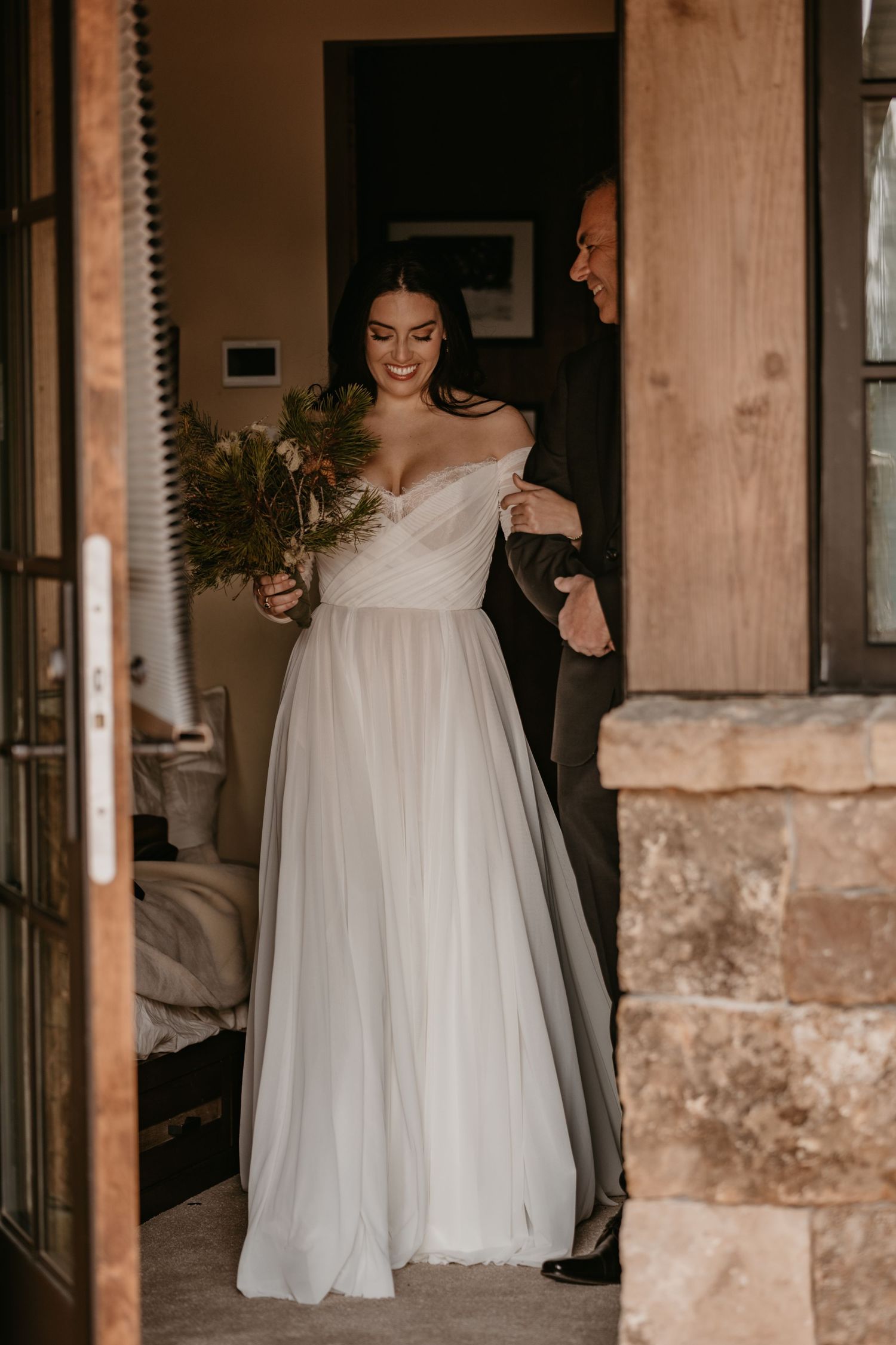 Elegant white wedding dress flowing through doorway in rustic venue setting.
