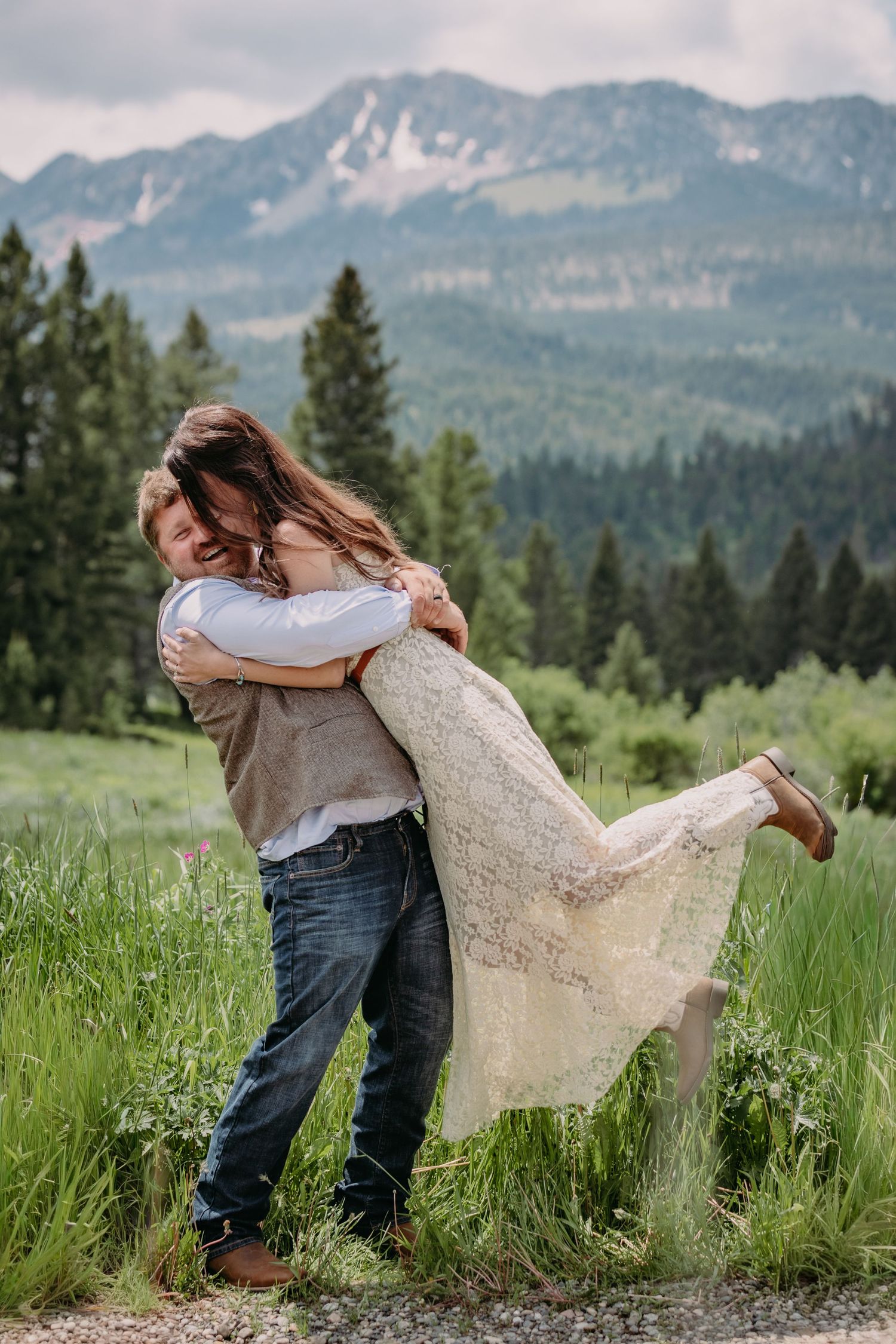 A joyful couple shares a playful dip in a mountain meadow during their wedding photoshoot.