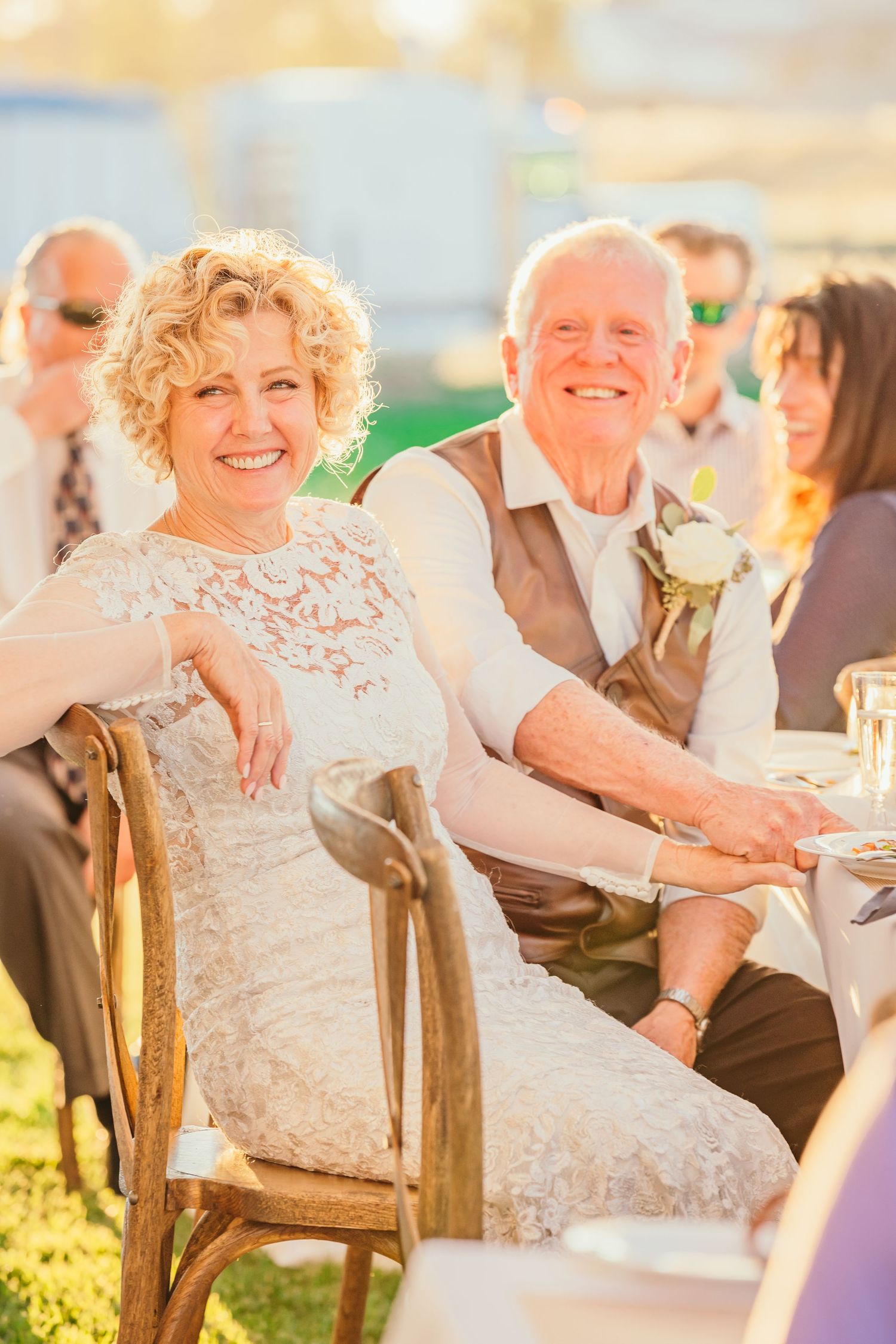 Wedding guests seated outdoors enjoying conversation during golden hour celebration.