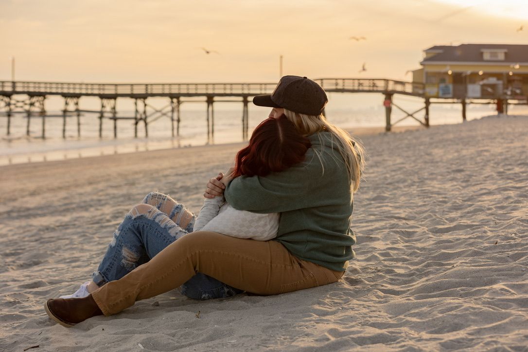 A romantic beach scene with a couple sitting together at sunset.
