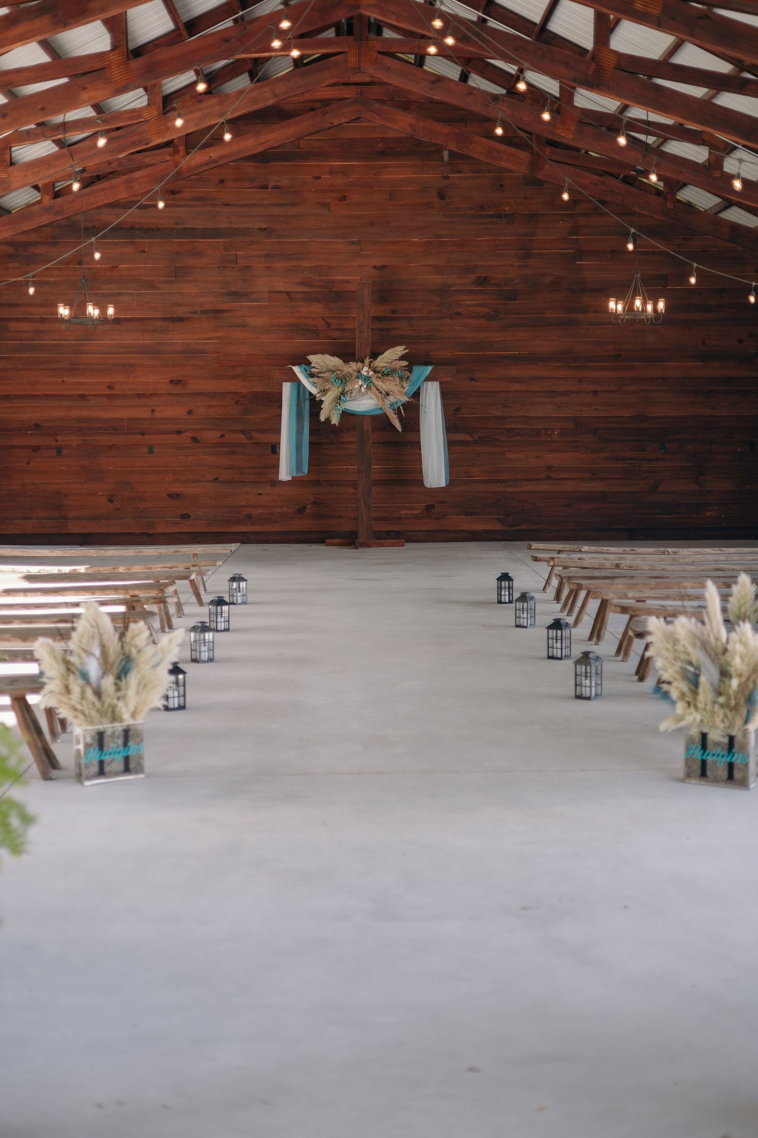 Rustic barn wedding venue interior with string lights and wooden beam ceiling.