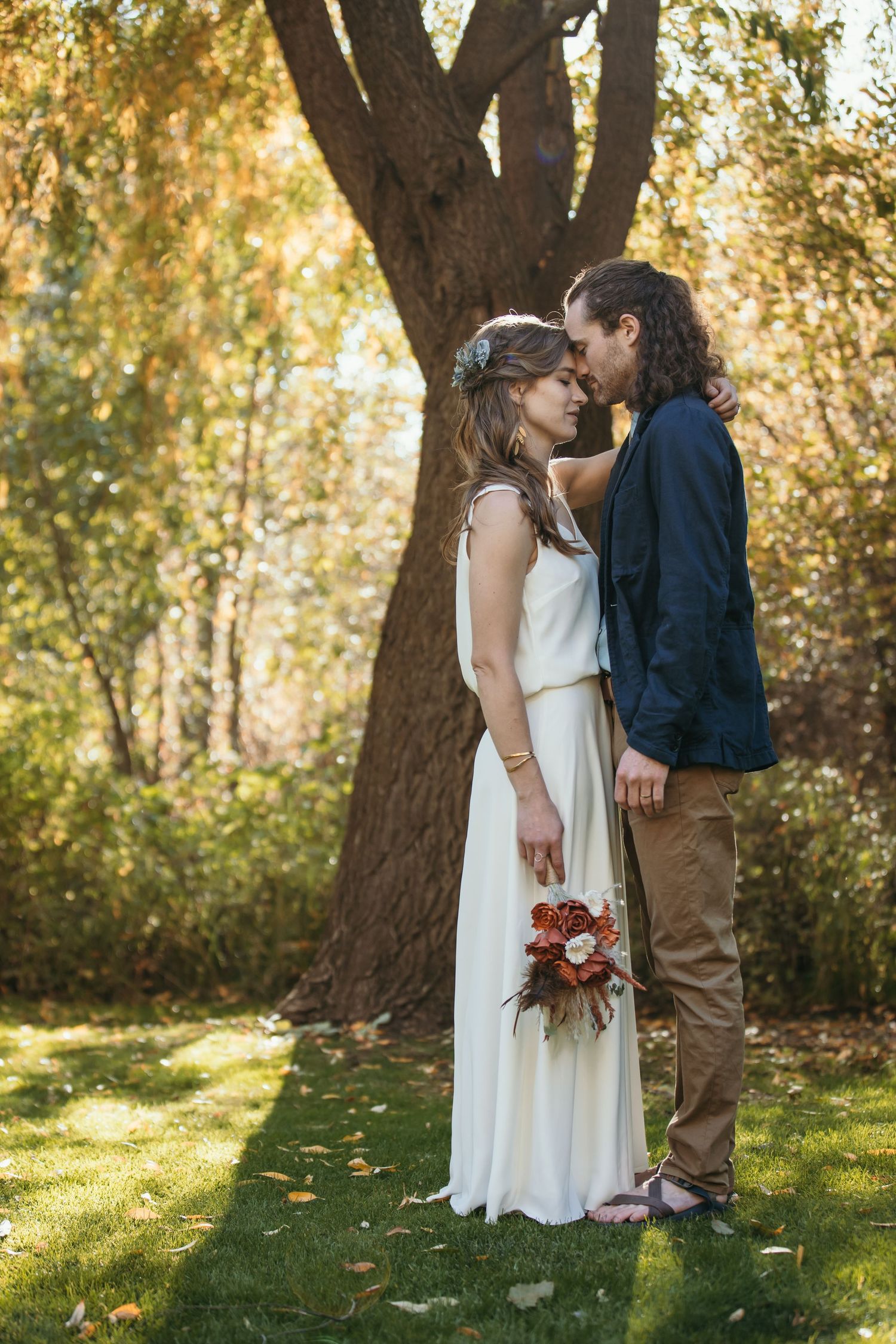 Autumn wedding portraits in a sunlit garden with white dress and natural scenery.