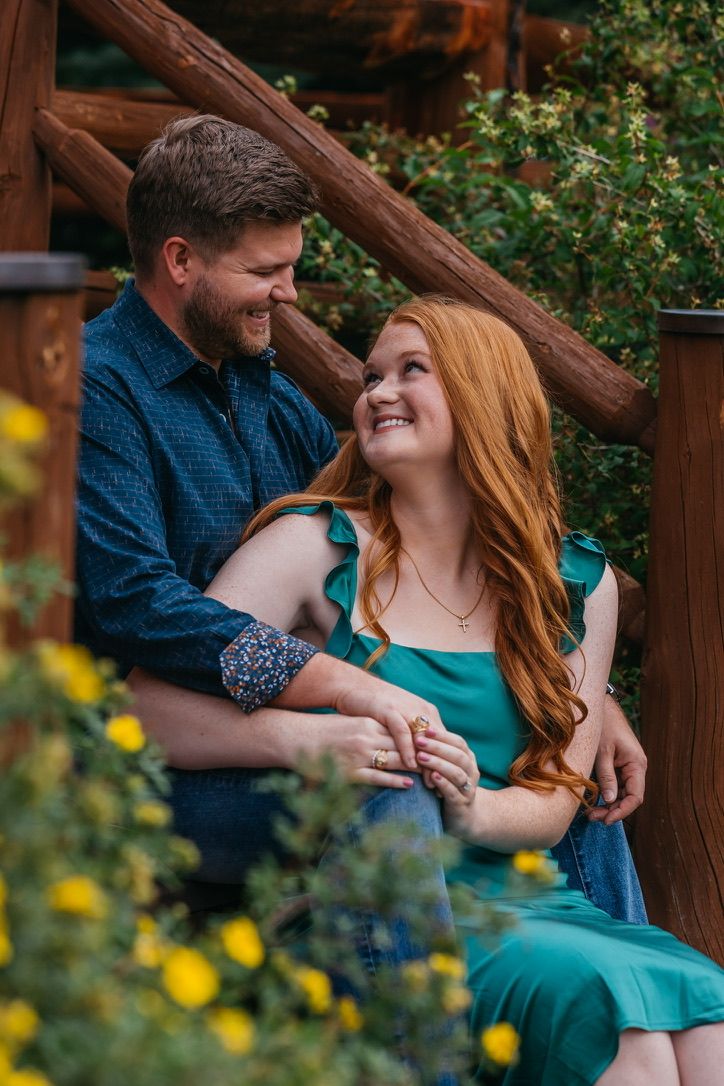 A couple shares loving glances while sitting on a rustic wooden porch.