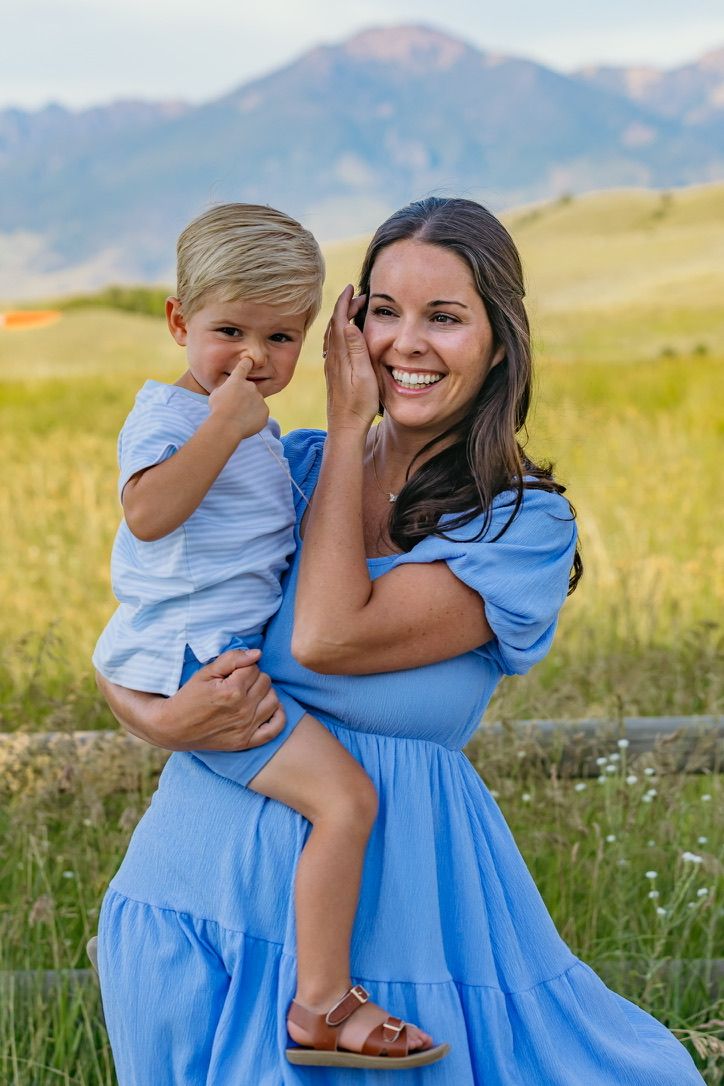 A light blue dress stands out against mountain scenery in a grassy meadow on a sunny day.