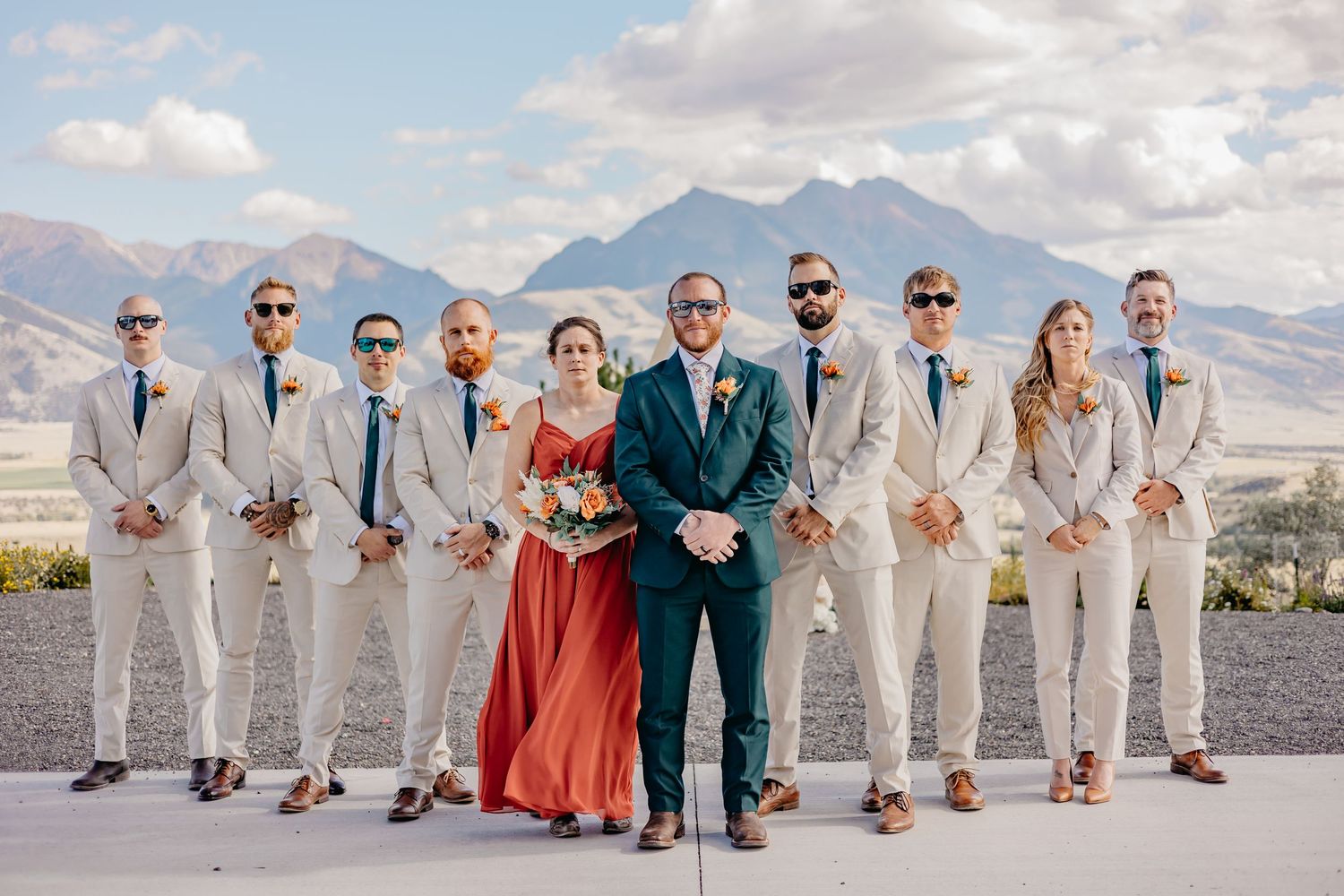 Wedding party lineup in light colored suits with mountain backdrop.