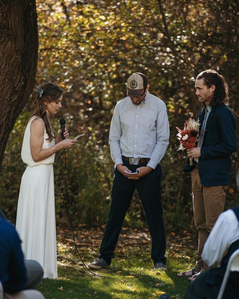 Intimate outdoor wedding ceremony in a wooded setting during autumn.