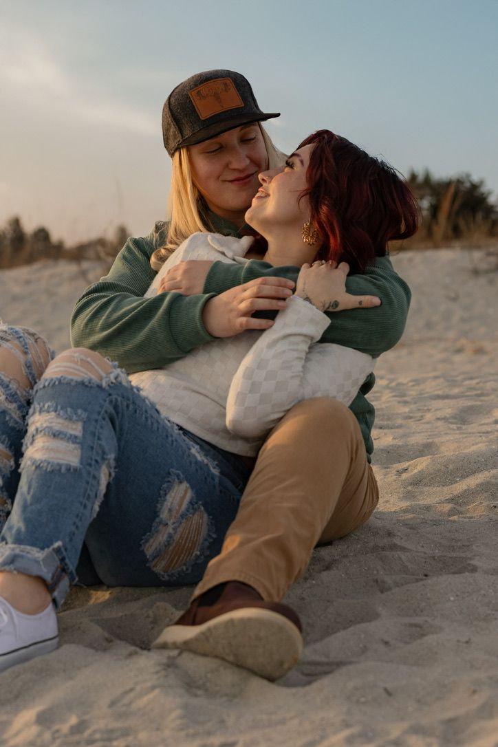 A couple shares intimate moments while lying on sandy beach at dusk.
