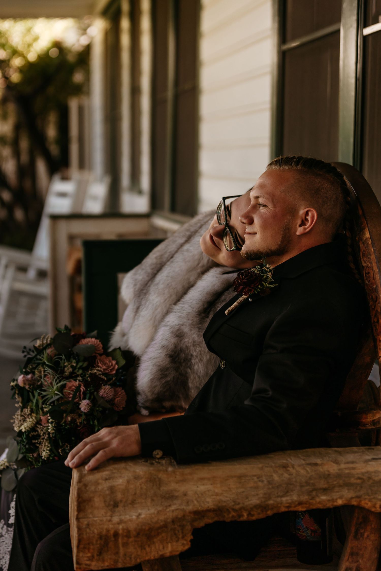 Person resting on rustic wooden bench with decorative floral arrangement nearby.