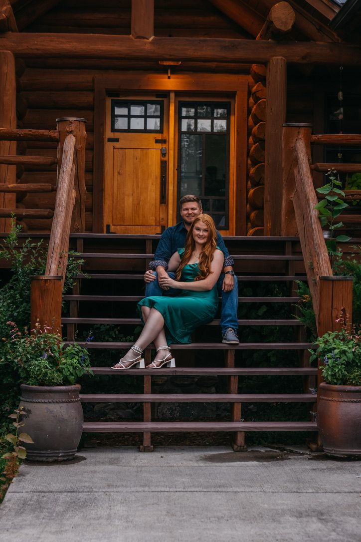 Couple relaxing on rustic cabin porch with wooden beams and potted plants.