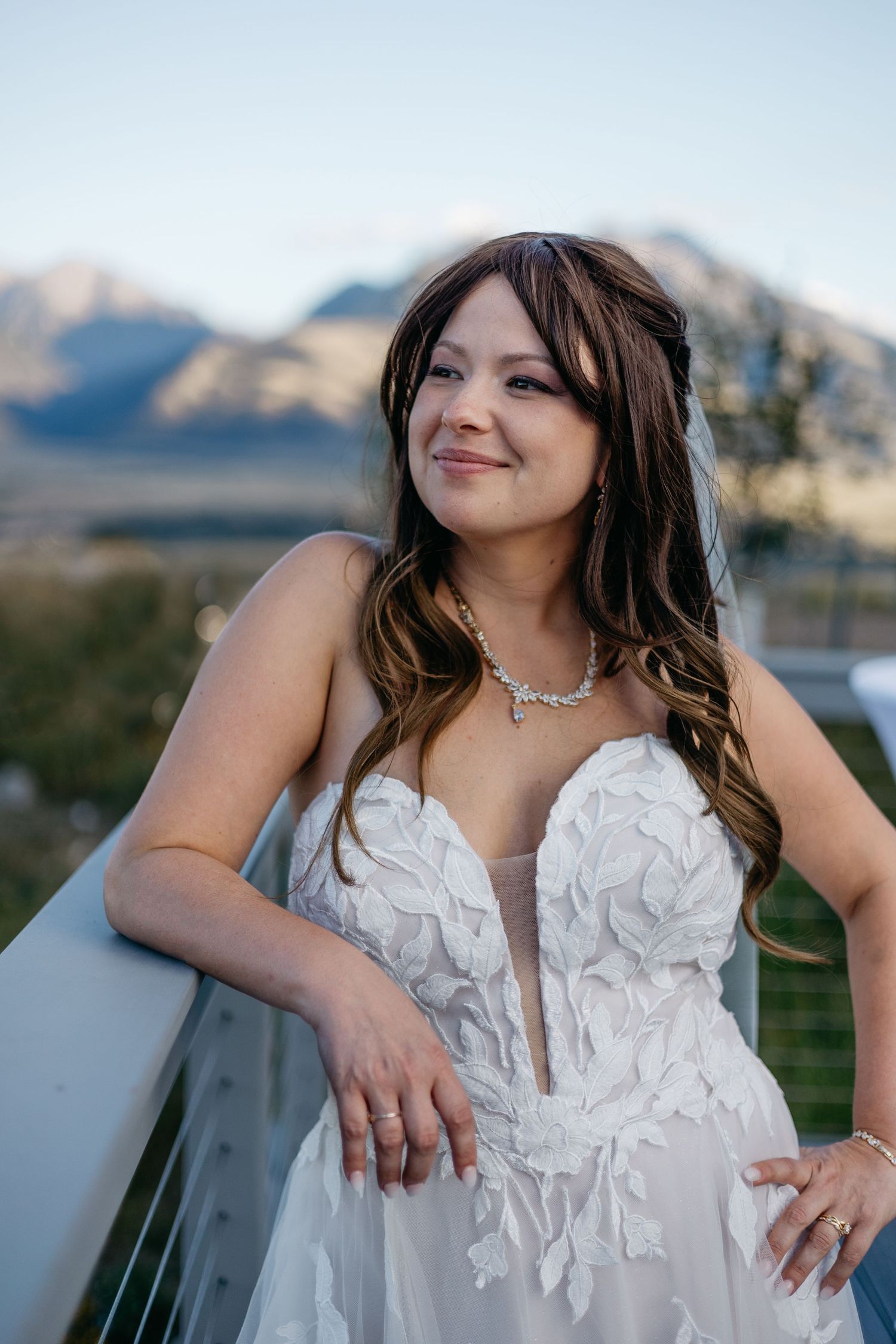 White wedding dress with textured floral details shown against mountain landscape backdrop.